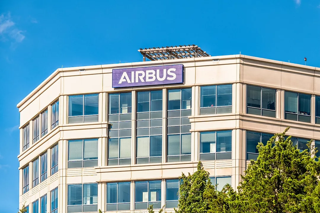 A white office building with a blue sign that reads "AIRBUS" positioned above the top floor windows