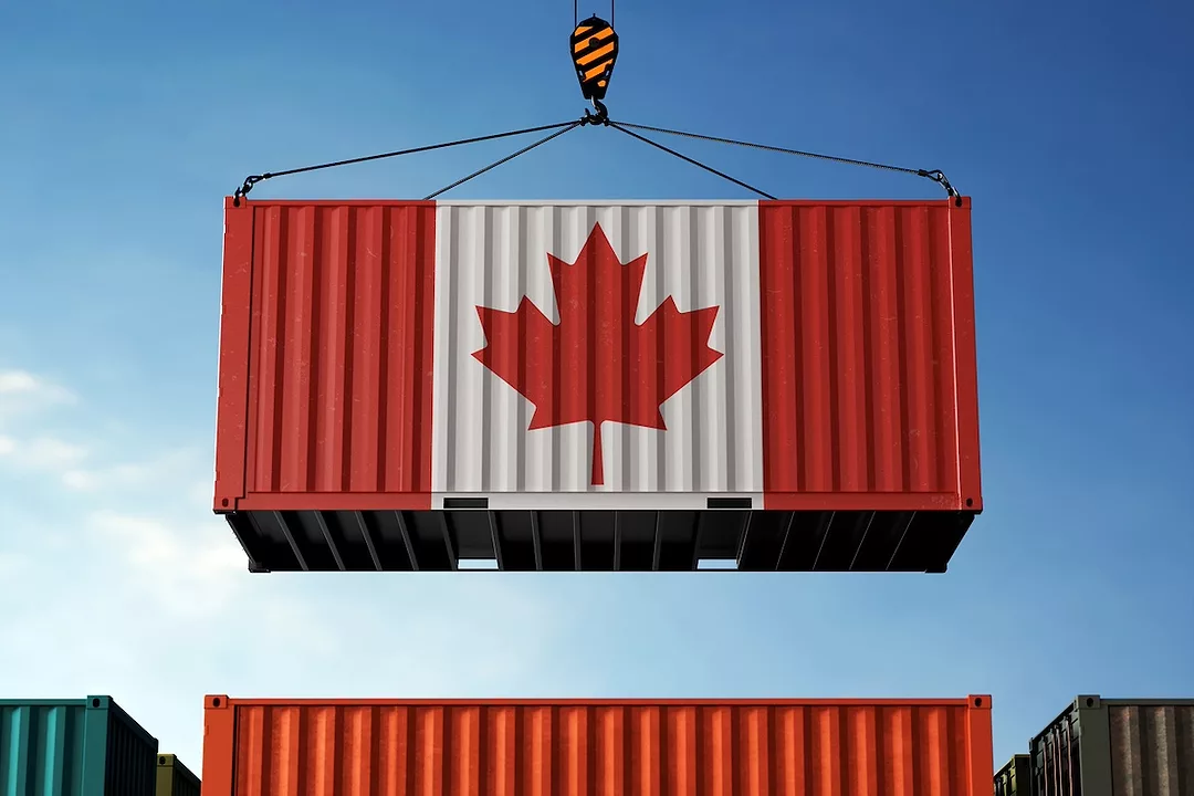 A shipping container painted with the Canadian flag being lifted by a crane