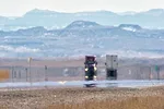 Heat Haze Distorts Video of Semi-Trucks Driving Down an Interstate Surrounded by Mountains on a Sunny Day