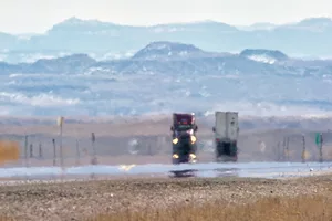 Heat Haze Distorts Video of Semi-Trucks Driving Down an Interstate Surrounded by Mountains on a Sunny Day