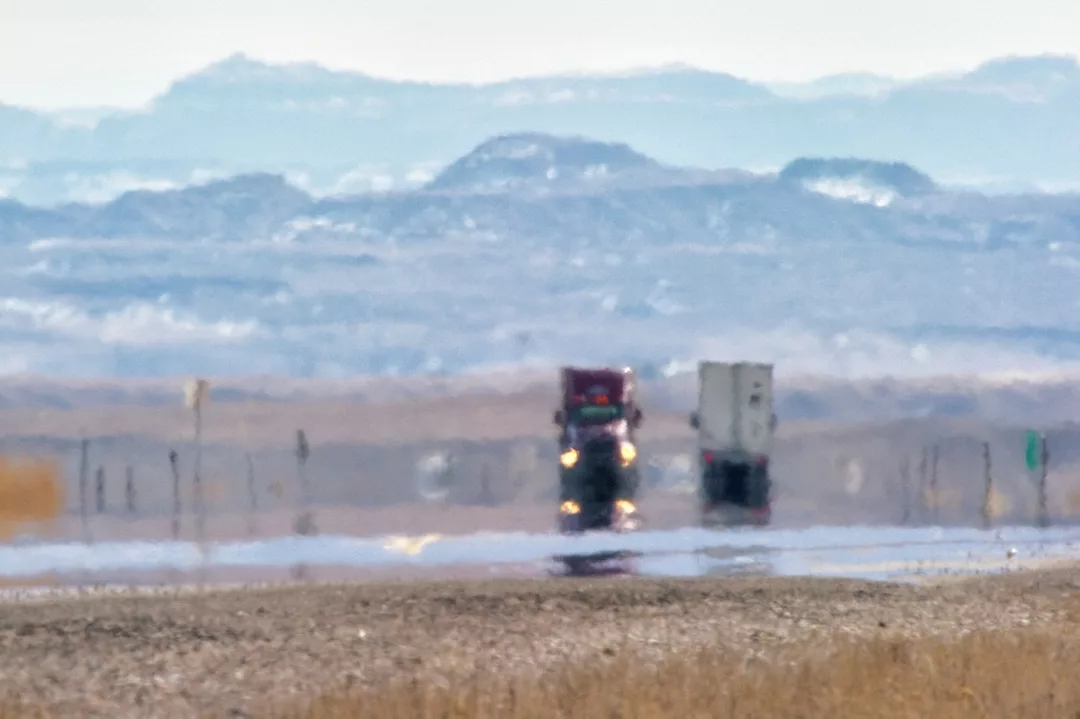 Heat Haze Distorts Video of Semi-Trucks Driving Down an Interstate Surrounded by Mountains on a Sunny Day