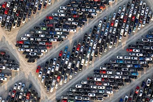 AN AERIAL VIEW OF HUNDREDS OF CARS IN STORAGE IN THE OPEN