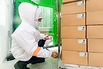 An employee in a warm suit crouches down to get boxes of food ready for shipping at a warehouse