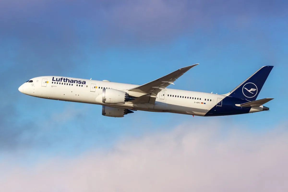 A LARGE AIRCRAFT BEARING THE LUFTHANSA LOG FLIES ABOVE FLUFFLY CLOUDS