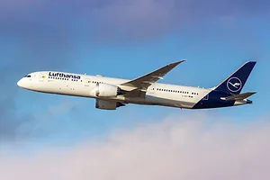 A LARGE AIRCRAFT BEARING THE LUFTHANSA LOG FLIES ABOVE FLUFFLY CLOUDS