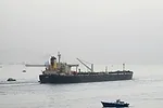 TANKER IN SUEZ CANAL SHIP AT SEA BLOOMBERG.jpg A SHIP PLIES A NARROW WATERWAY, FLANKED BY SMALLER BOATS