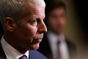 A CLOSE UP OF THE FACE OF A MIDDLE-AGED MAN IN A SUIT AND TIE