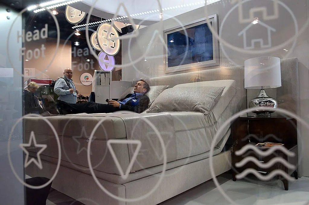 A MAN LIES ON A MATTRESS IN A MATTRESS SHOWROOM
