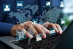 HANDS TYPE ON A KEYBOARD UNDER A SUPER IMPOSED DIGITIZED MAP OF THE WORLD, ALONG WITH IMAGES OF A SHIP, A SHOPPING CART AND OTHER SYMBOLS OF INTERNATIONAL LOGISTICS