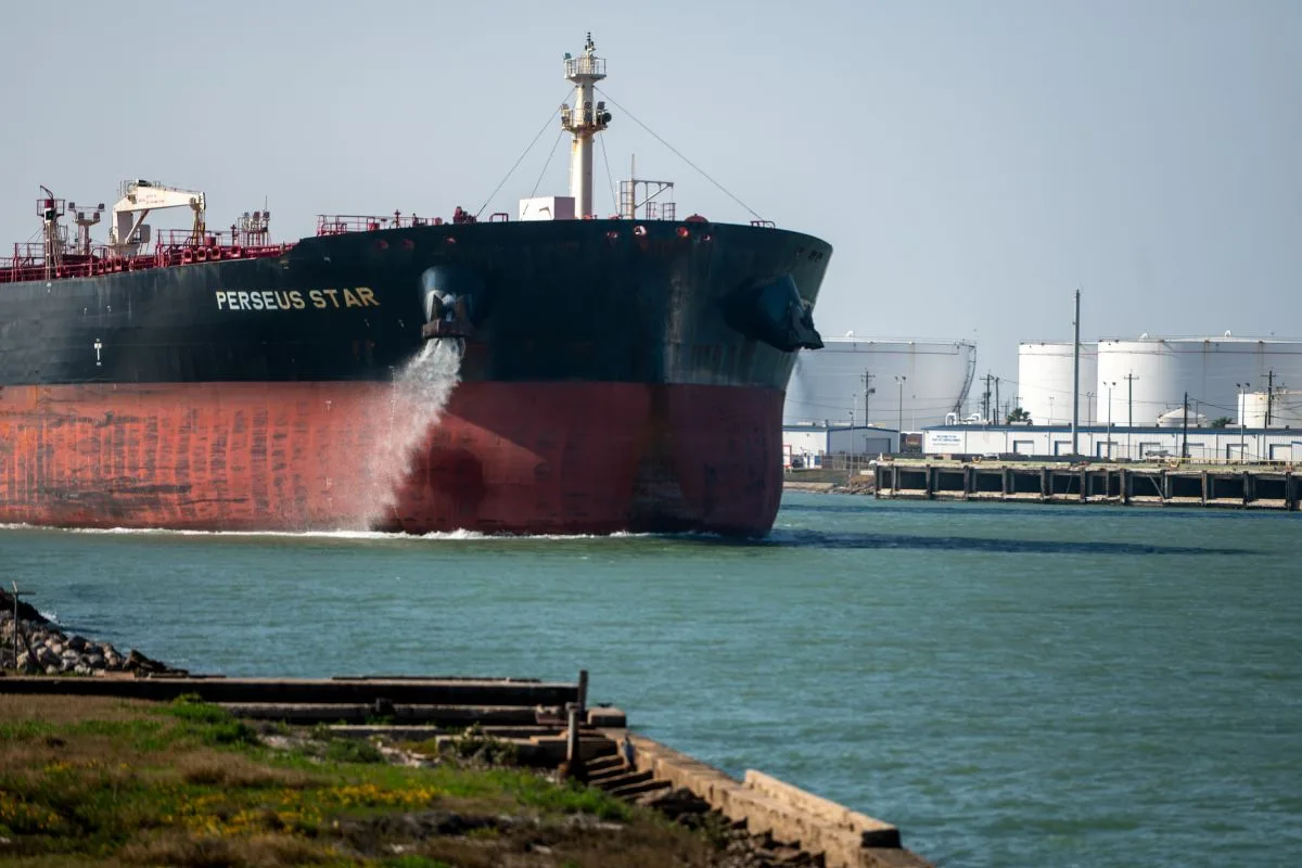 A LARGE BLACK AND RED OIL TANKER ENTERS A PORT