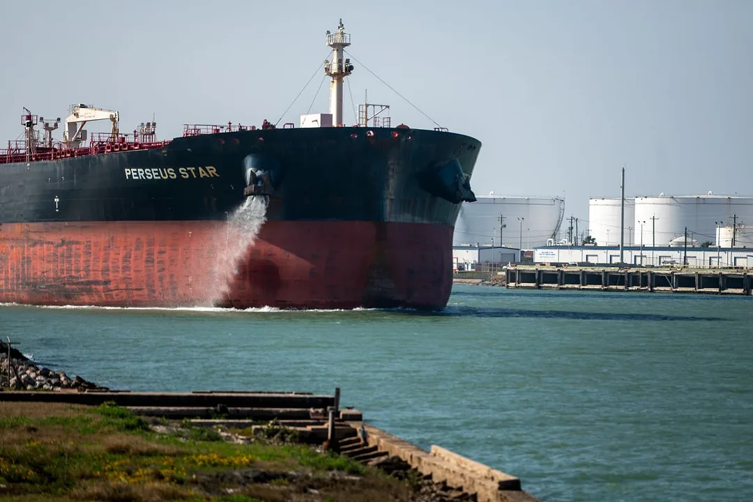 A LARGE BLACK AND RED OIL TANKER ENTERS A PORT