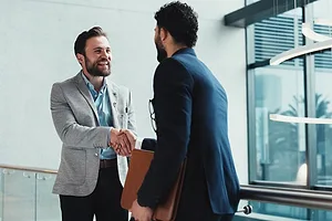 TWO BEARDED MEN IN SUITS SHAKE HANDS ENTHUSIASTICALLY