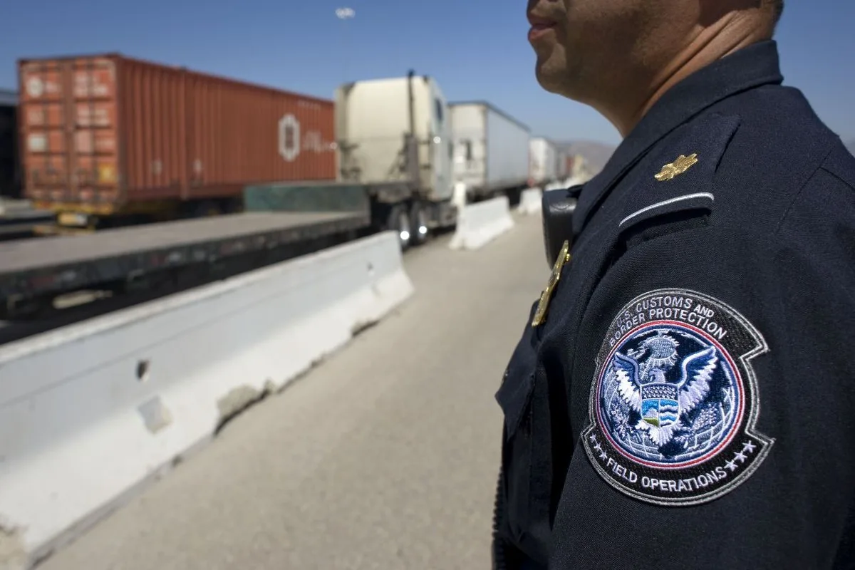A UNIFORMED OFFICER STANDS NEAR A HIGHWAY WITH TRUCKS ON IT