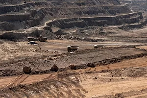 A tier hillside overlooking a cobalt mine, lined with browned, dry grass and desert terrain