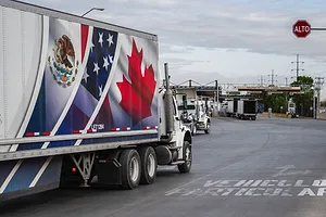 A TRUCK BEARING A LOGO COMBINING THE FLAGS OF MEXICO, THE US AND CANADA, APPROACHES A BORDER CROSSING