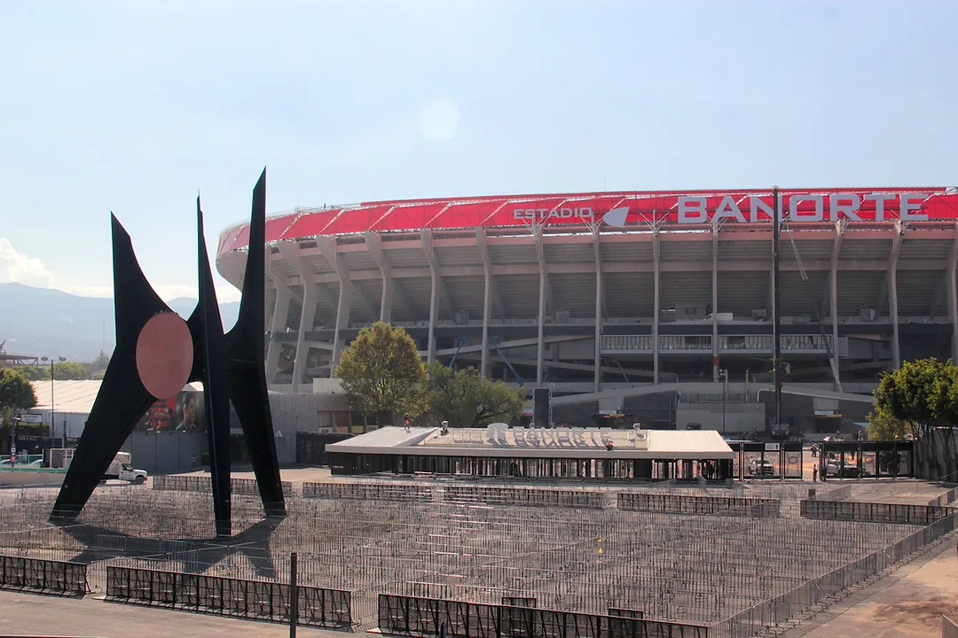 A grey concrete soccer stadium with a red lining around the upper edge of the bowl