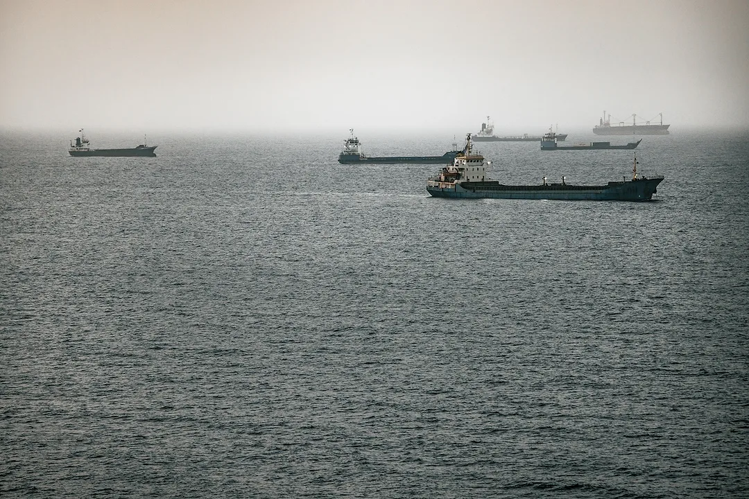 A group of container ships at sea on a cloudy day