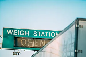 A Semi Truck Passing a "Weigh Station" Sign along an Interstate highway