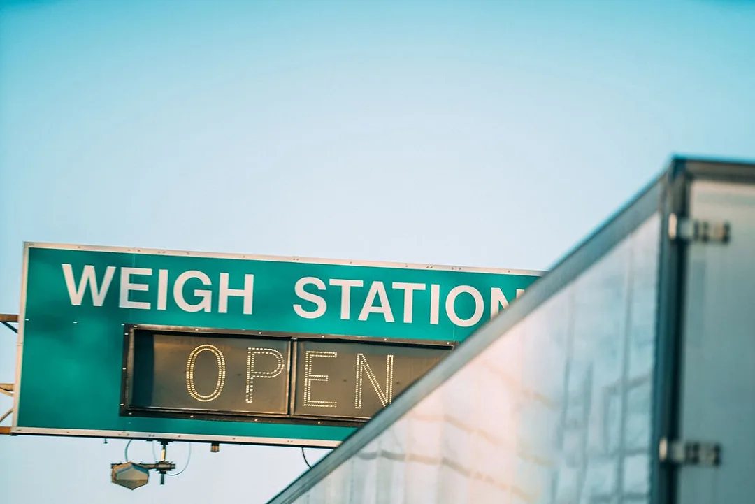 A Semi Truck Passing a "Weigh Station" Sign along an Interstate highway