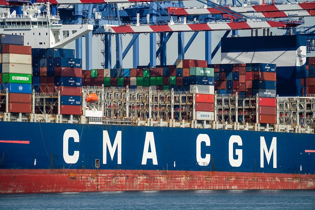 A blue container ship with "CMA CGM" written across its side in white lettering, docked at a port