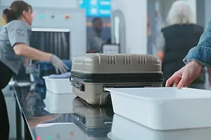 Air passengers Putting Personal Items and Baggage through X-ray Scanning at an airport security checkpoint