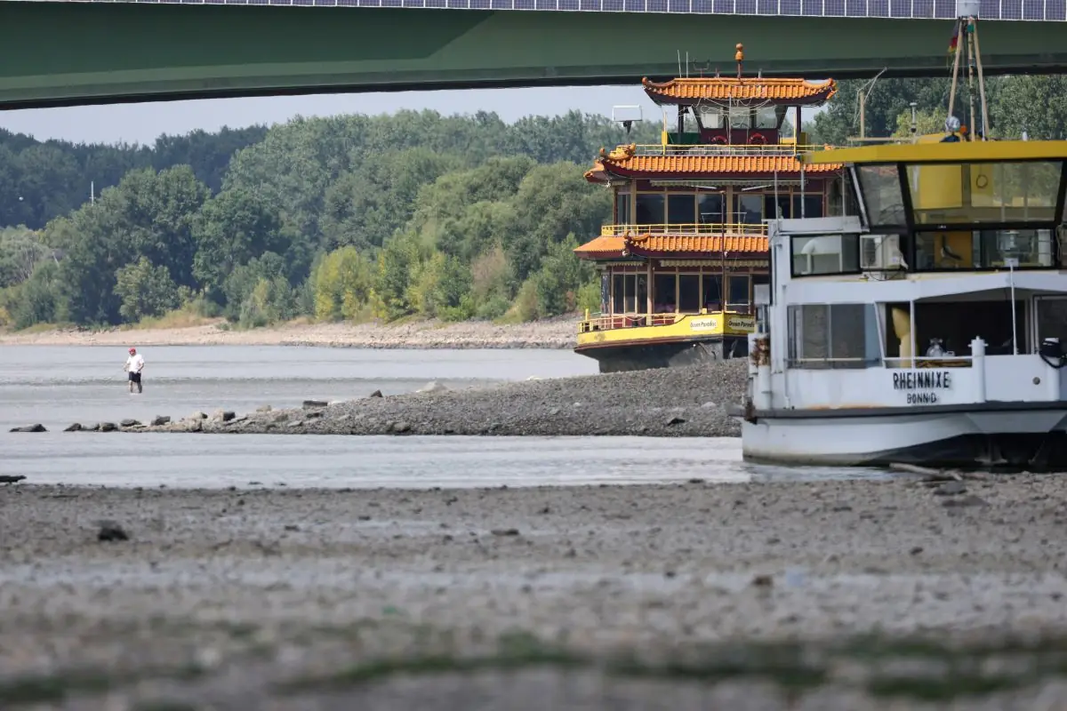 TWO PASSENGER BOATS SIT STRANDED ON A RIVER BED WITH LITTLE WATER IN IT