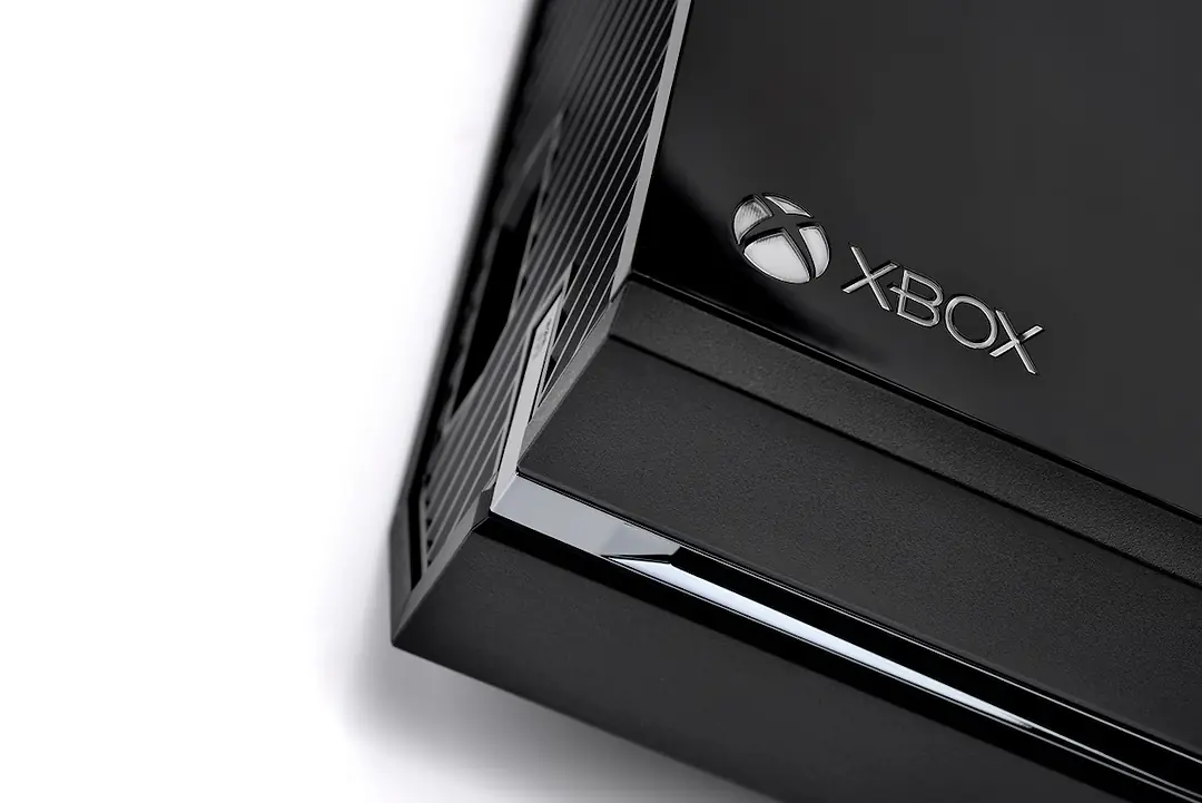 The corner of a rectangular black gaming console, with an "XBOX" logo printed along the edge