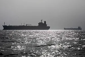 TWO LARGE CARGO SHIPS ANCHORED OUT ON A SILVERY SEA