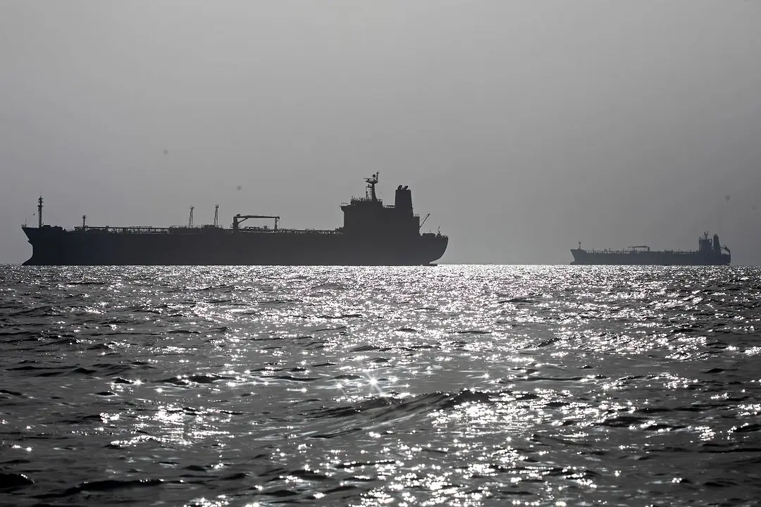 TWO LARGE CARGO SHIPS ANCHORED OUT ON A SILVERY SEA