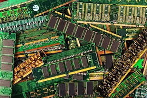 A pile of green circuit boards with gold wires attached to each