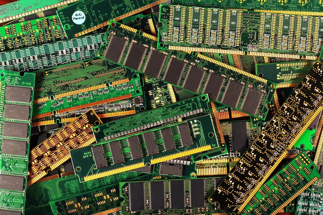 A pile of green circuit boards with gold wires attached to each