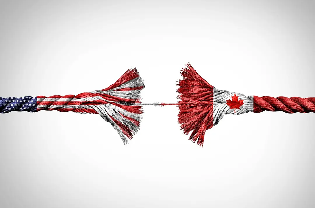 A ROPE COLORED LIKE THE CANADIAN AND US FLAGS ON EITHER END IS FRAYED IN THE MIDDLE, A SINGLE STRAND HOLDING IT TOGETHER