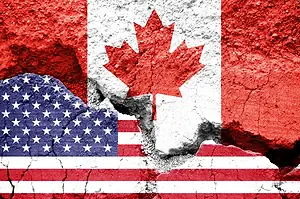 Images of the Canadian and American flags on concrete, with a crack running across them horizontally