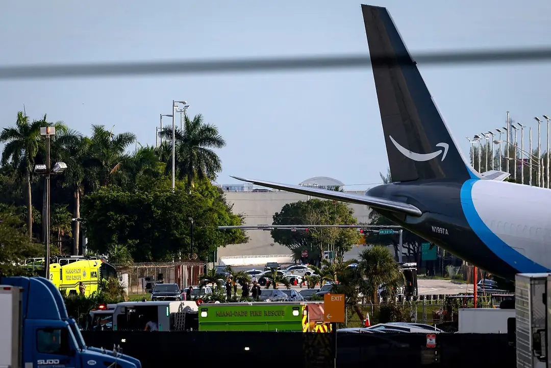 IN A CHAOTIC SCENE, EMERGENCY VEHICLES SURROUND THE TAIL END OF A PLANE