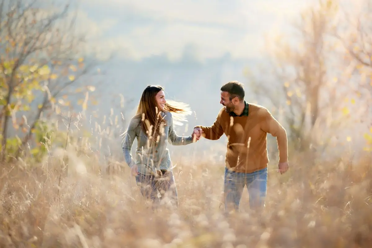 Couple holding hands in a field romantic partnership istock skynesher 1805372962