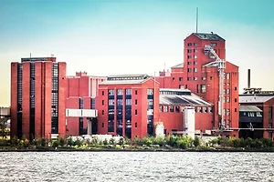 A LARGE RED-BRICK FACTORY SITS ON THE SHORES OF A LAKE