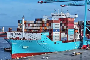 A blue container ship stacked with shipping containers sitting at a port