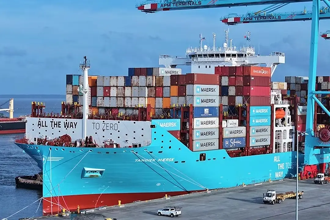 A blue container ship stacked with shipping containers sitting at a port