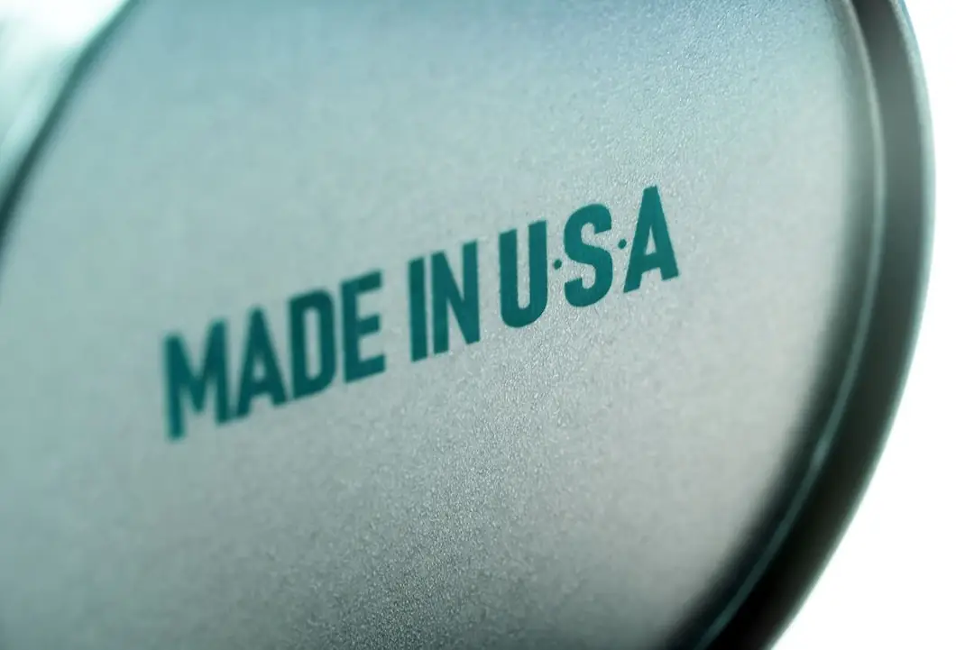 MADE IN USA IS STAMPED ON THE BOTTOM OF A ROUND OBJECT, SLIGHTLY OUT OF FOCUS