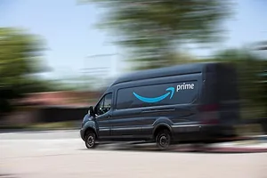 A VAN BEARING THE AMAZON PRIME LOGO IS SET AGAINST A BLURRED BACKGROUND, INDICATING FORWARD MOVEMENT