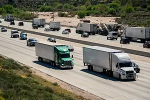 TRUCKS DRIVE DOWN A BUSY 10-LANE HIGHWAY