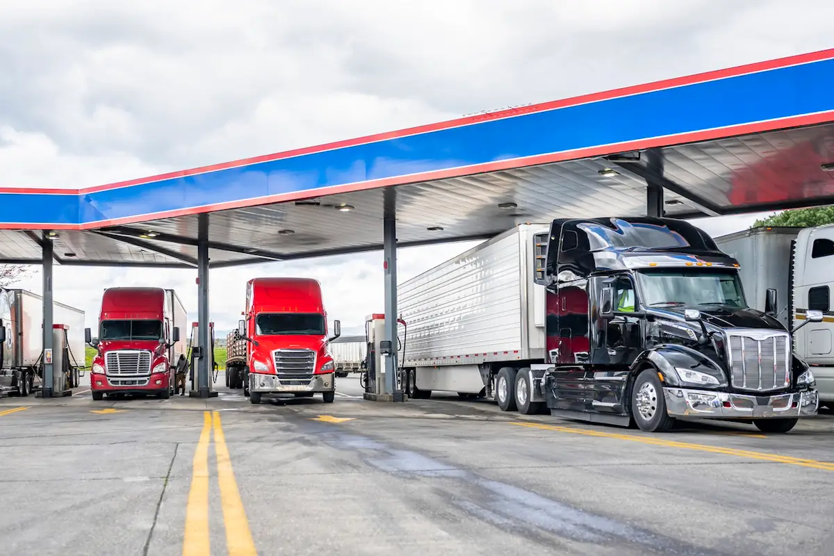Three semi-trucks parked at a gas station