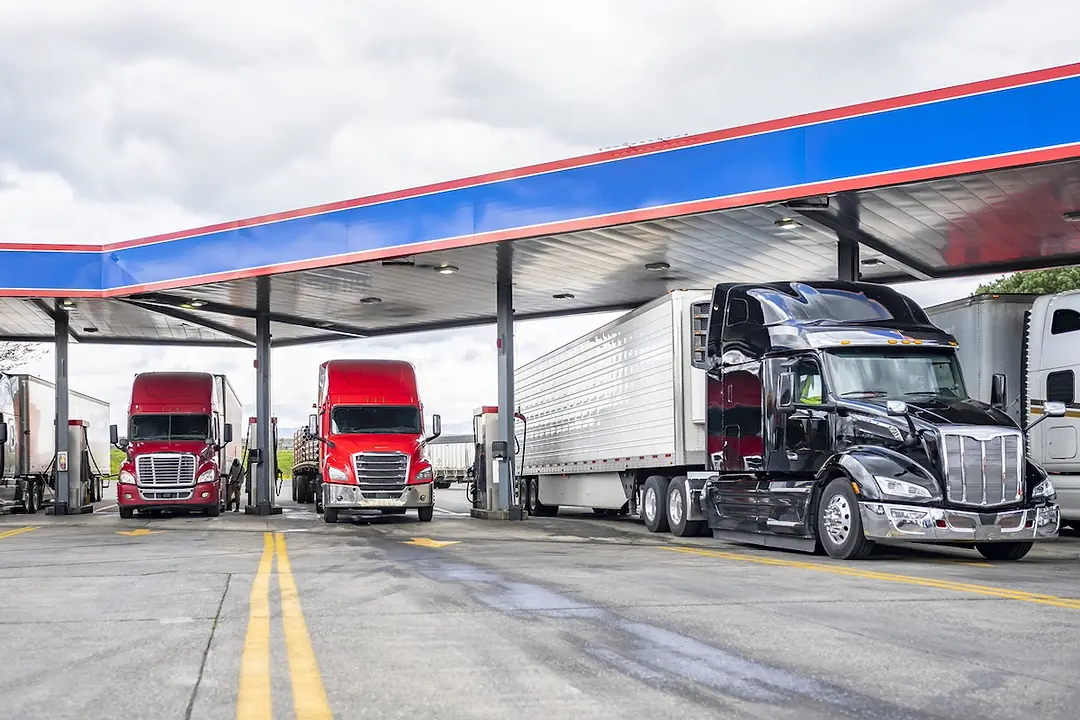 Three semi-trucks parked at a gas station