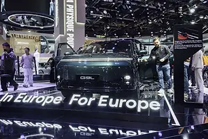 A SHINY NEW CAR WITH ITS DOORS OPEN SITS AMONG THE GLITZ OF AN INTERNATIONAL CAR SHOW