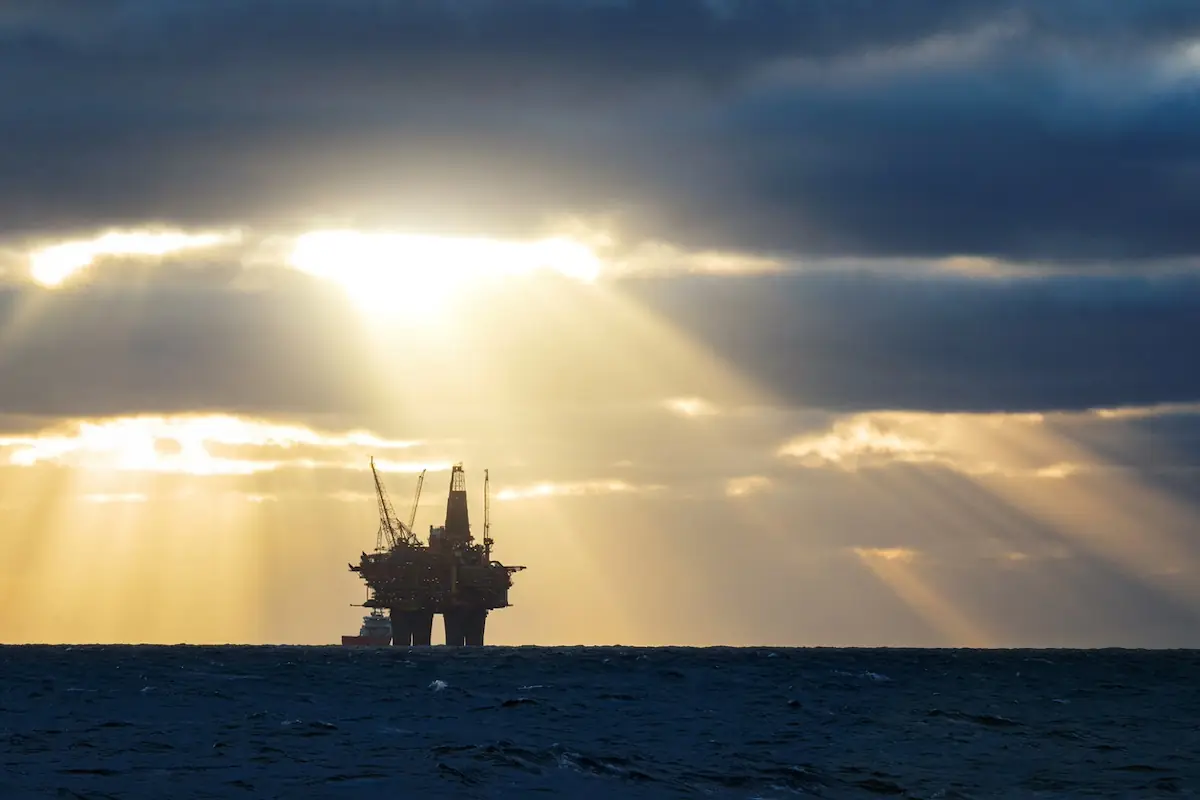 An oil rig in the middle of the ocean at sunset on a cloudy day