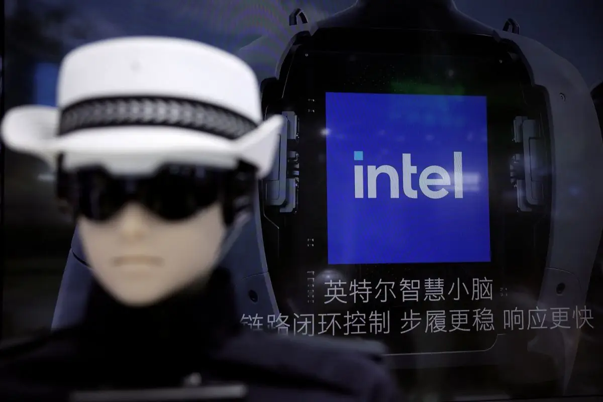 AN OUT OF FOCUS WOMAN IN A BLACK AND WHITE HAT LOOMS IN FRONT OF AN INTEL SIGN