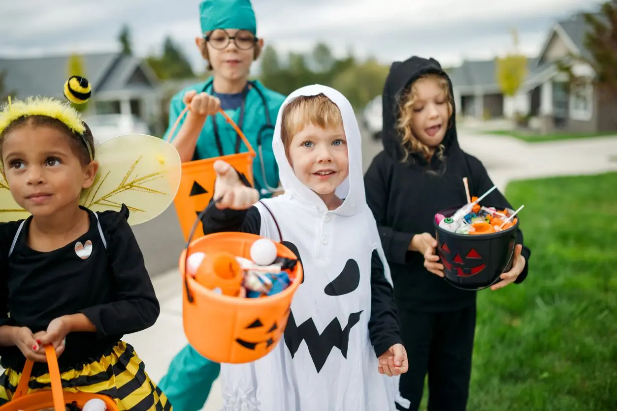 Children Trick Or Treat For Halloween In Residential Neighborhood