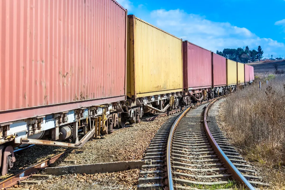 A freight train pulling yellow and red cargo containers